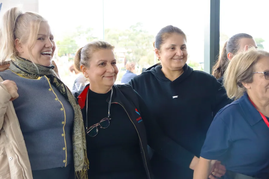 A group of People First Healthcare team members standing arm in arm and smiling