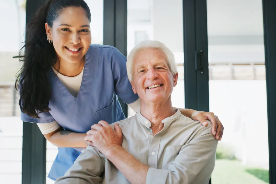 A People First Healthcare carer standing with an older man, both smiling