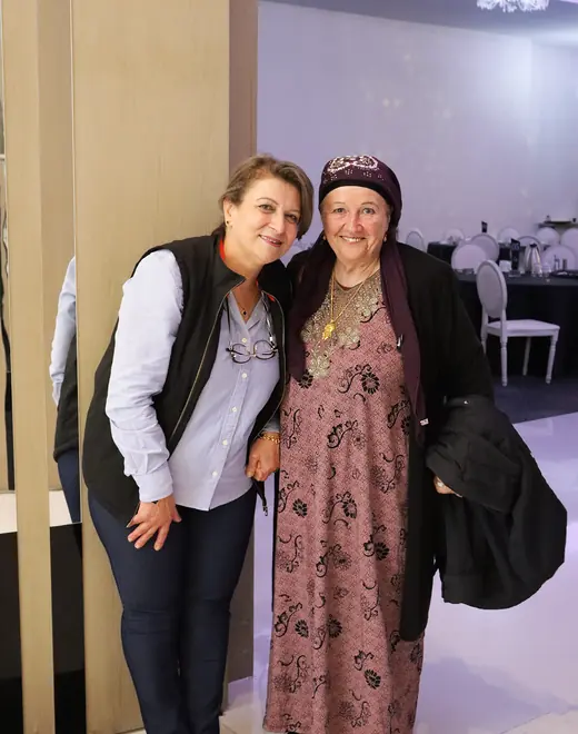 A People First Healthcare carer standing arm in arm with an older woman in a headscarf
