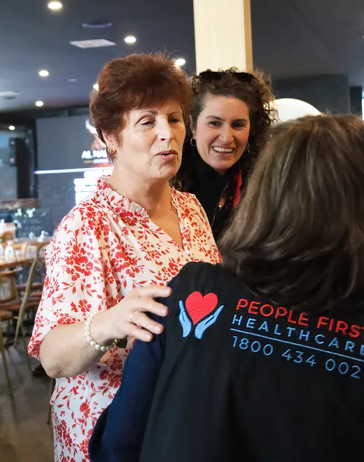 Two People First Healthcare team members talking with an older woman at a community event
