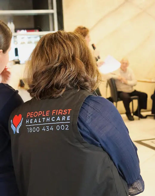 A People First Healthcare team member in a branded vest at a community centre session