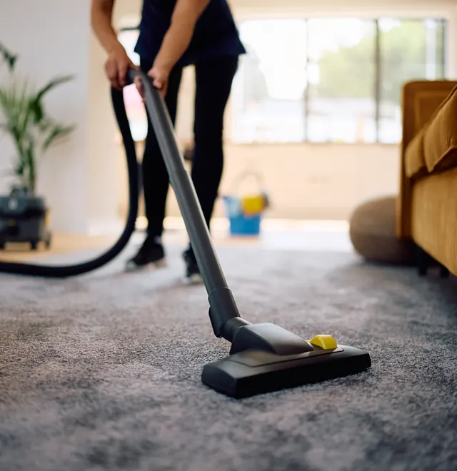 A People First Healthcare support worker vacuuming a client's living room