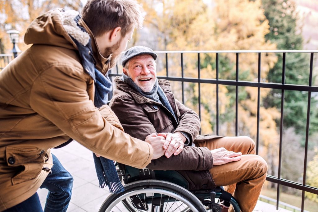 Senior father in wheelchair and young son on a walk.