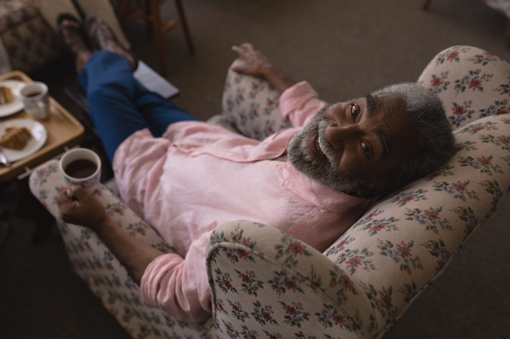 Senior man having black coffee and looking the camera with smile in living room at home